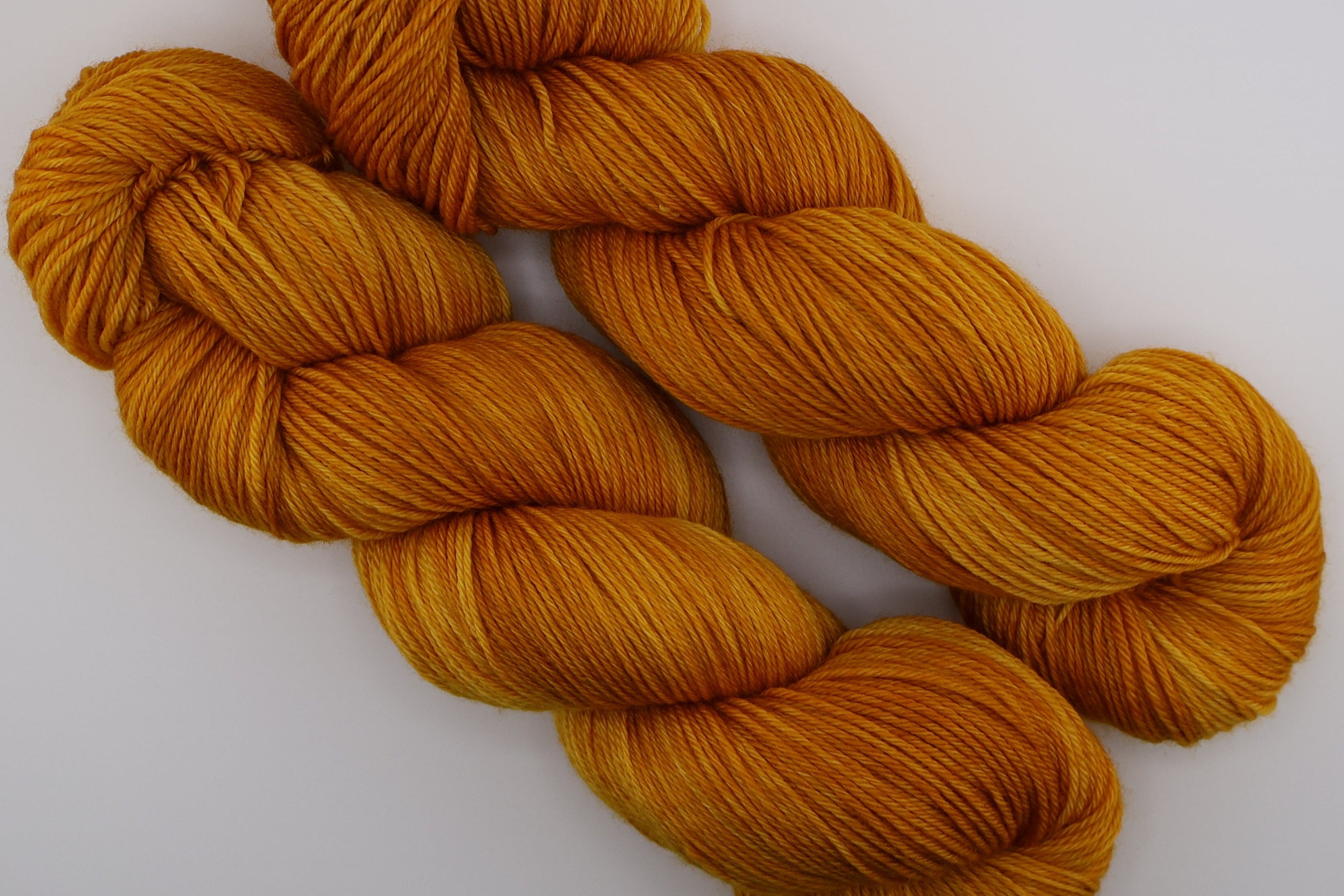 Two skeins of orange yarn on a white background